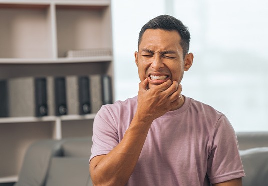 Man touching corners of his mouth squinting in pain