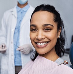Woman with dark hair in dental chair with dentist behind her