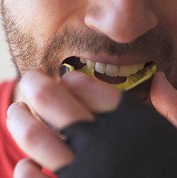 Man in red shirt inserting yellow mouthguard
