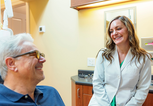 Senior man in the dental chair grinning at his dentist