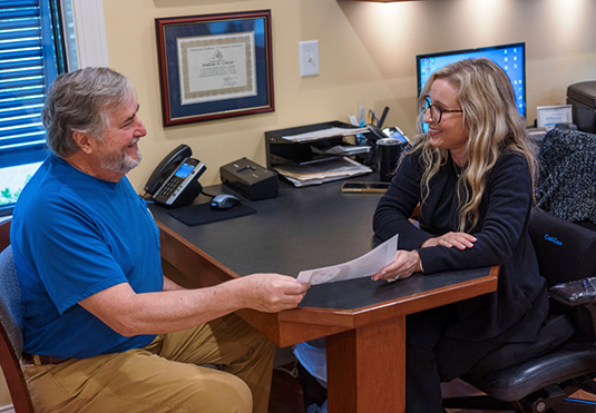 Man at desk with a dental team member holding paperwork