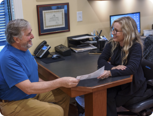 Man sitting across desk from dental team member with paperwork