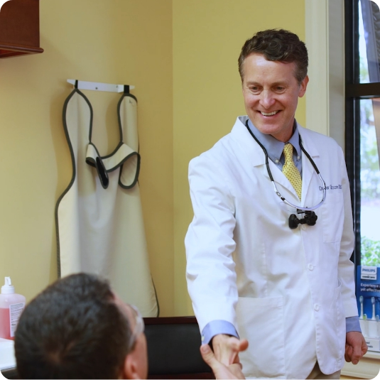 Smiling Mount Pleasant dentist shaking hands with a patient in the treatment chair