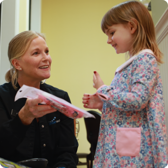 Dental team member giving a young girl patient a packet